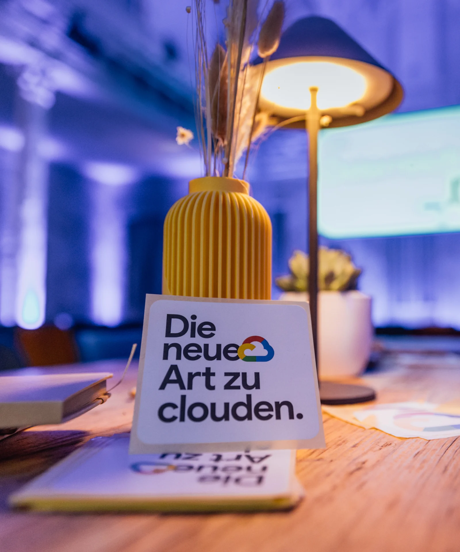 Nahaufnahme eines Tisches mit dem Schriftzug „Die neue Art zu clouden“ in einem atmosphärisch beleuchteten Raum auf dem Google Cloud Summit.