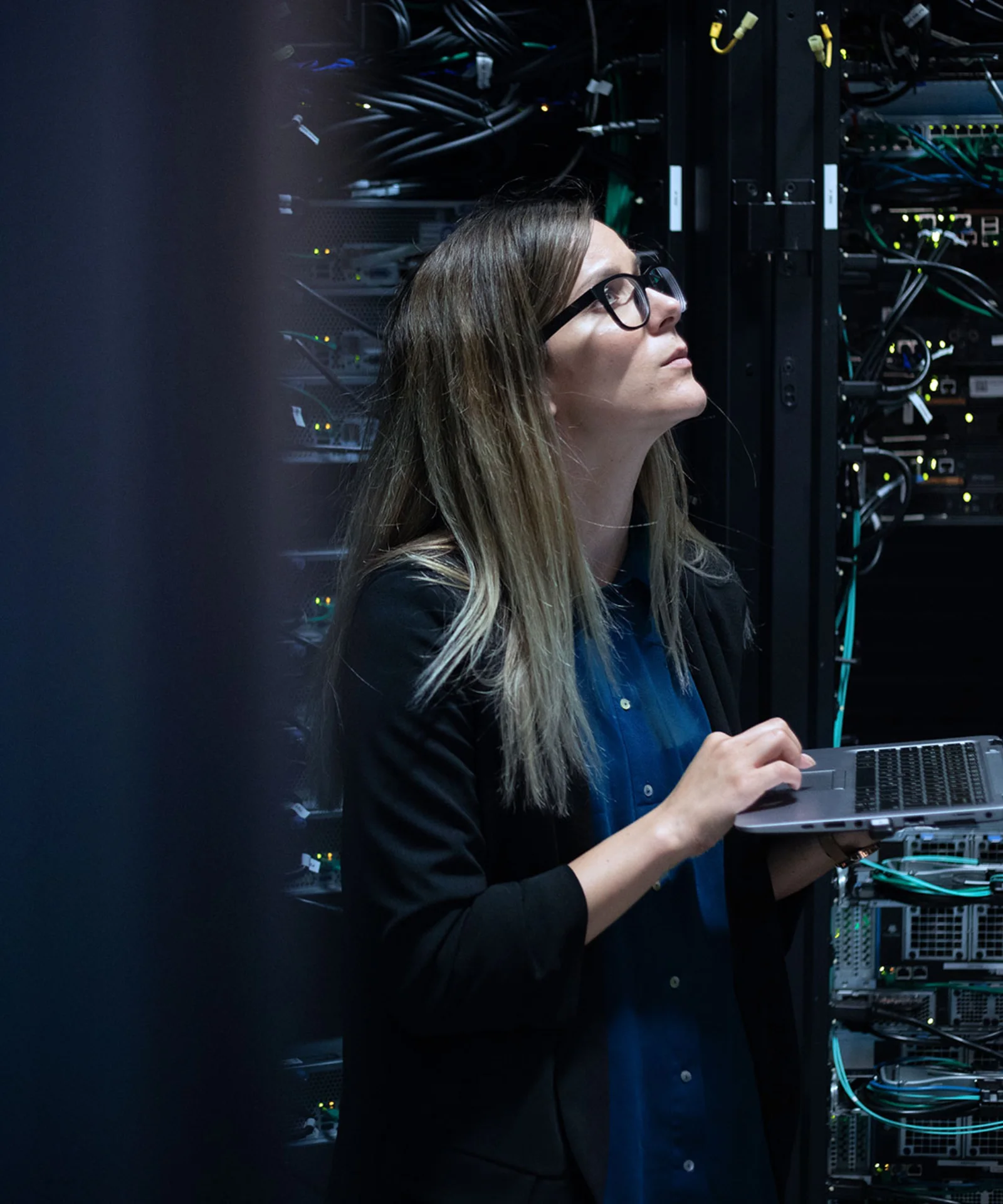 High Performance Computing (HPC) in the cloud is suitable for all complex calculations. However, the technology is particularly useful for applications in capital markets, insurance and industrial IoT. <br/>Key visual depicting an IT professional managing high-performance computing (HPC) solutions. The image features a woman working on a laptop in a server room, surrounded by networking cables and server equipment.