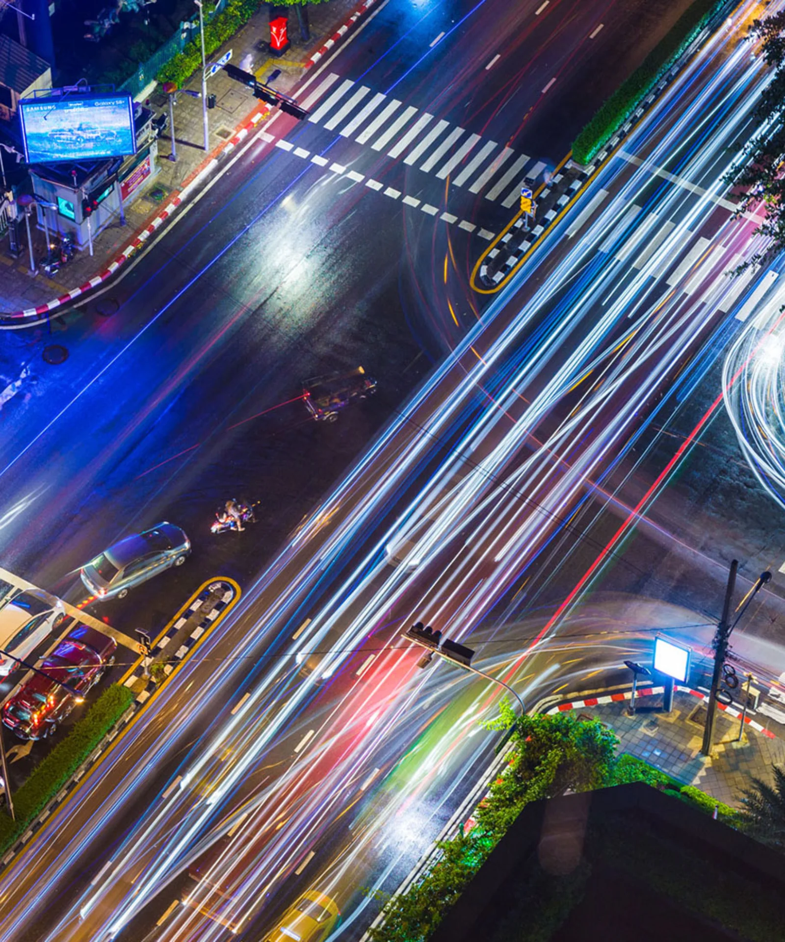 Una vista aérea de una intersección concurrida de la ciudad por la noche, con rayos de luz que representan el tráfico en rápido movimiento y simbolizan la naturaleza dinámica de las soluciones de seguros personalizadas.