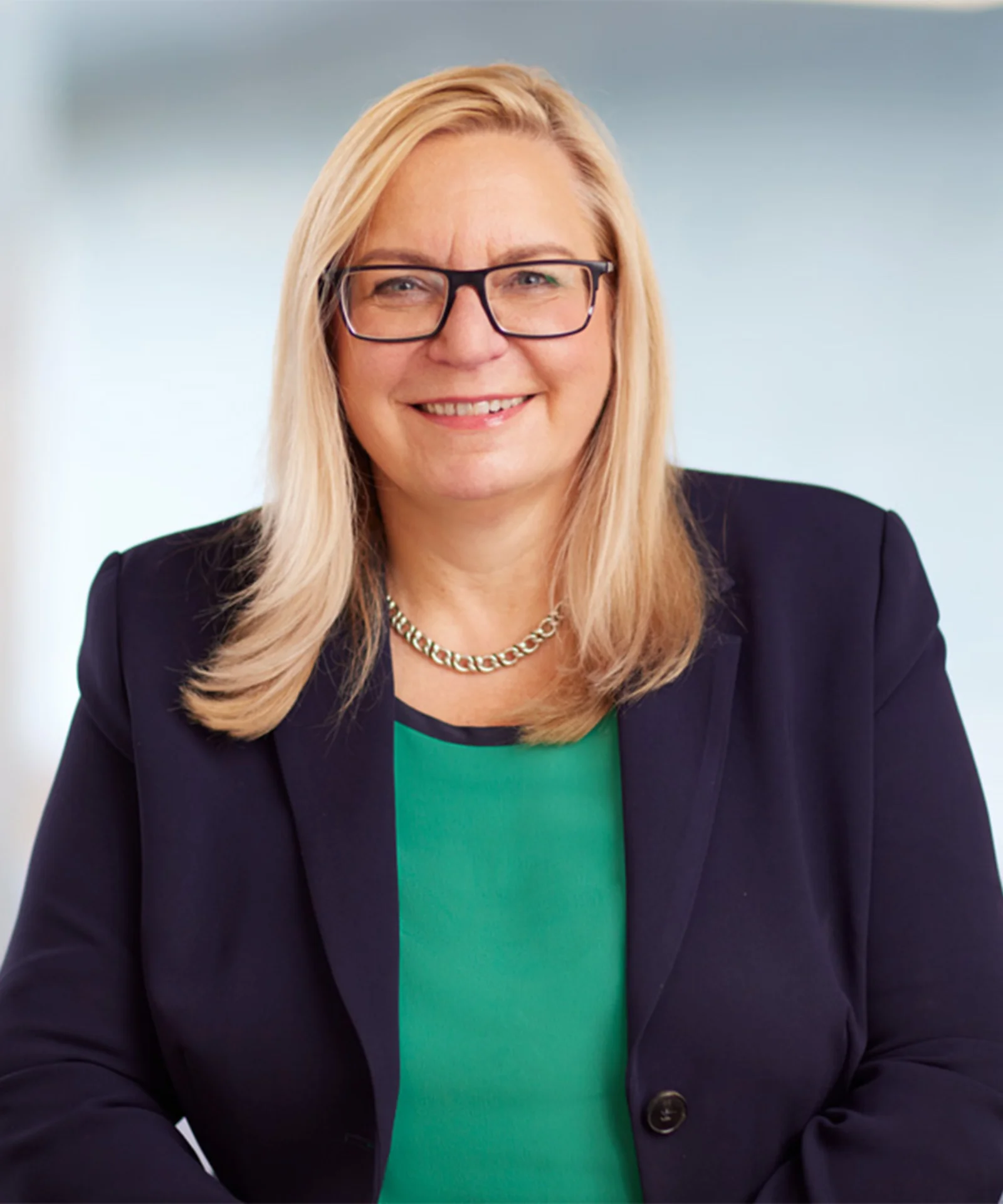 Marika Lulay, a member of the GFT Administrative Board, smiling confidently while wearing a navy blazer and green top, symbolising leadership and expertise in the technology industry.