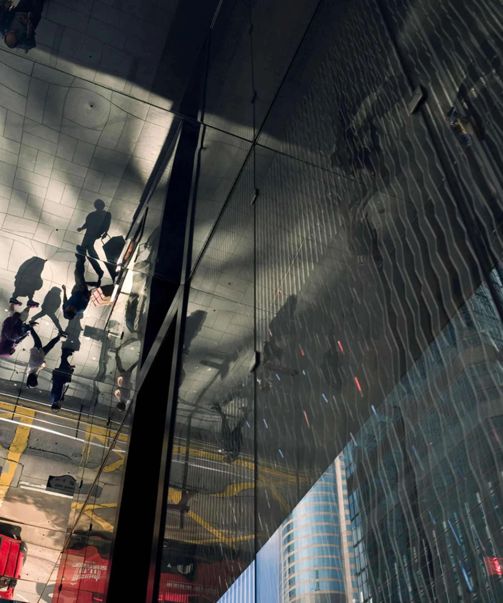 Reflection of cityscape and pedestrians in a glass building facade, symbolising modern financial interconnectedness.