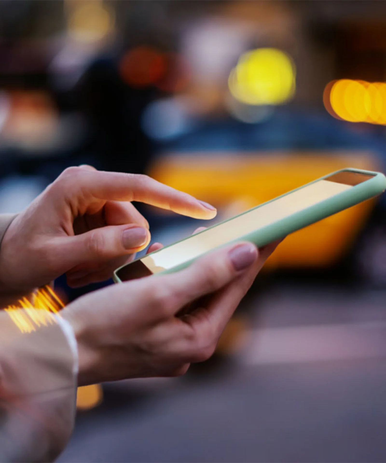 Close-up of a person using a mobile device on a busy city street, symbolising the modernisation efforts of a global bank to enhance digital banking services.