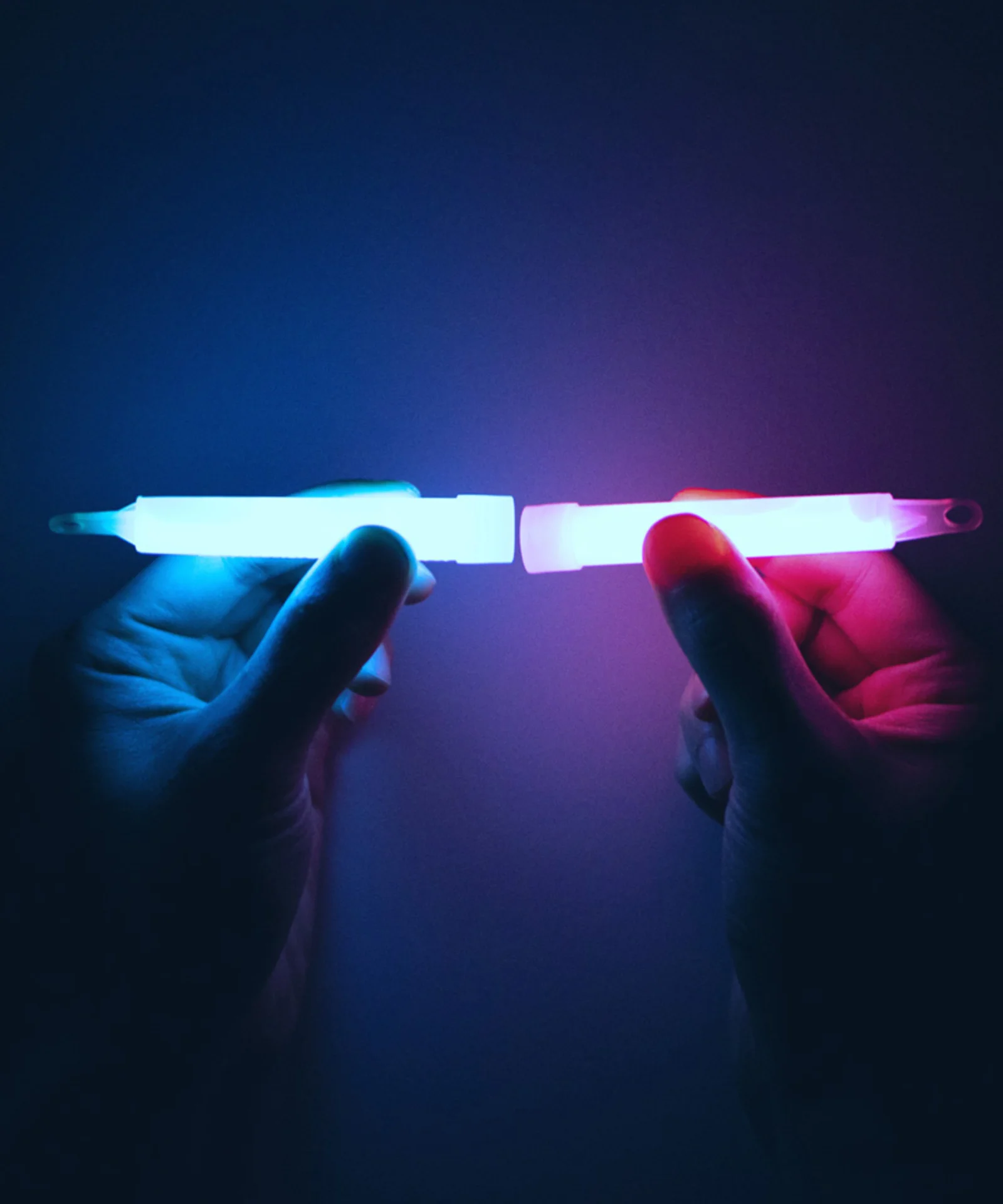 Two hands holding glowing light sticks, one blue and one pink, symbolizing the fusion and connection in platform modernisation.