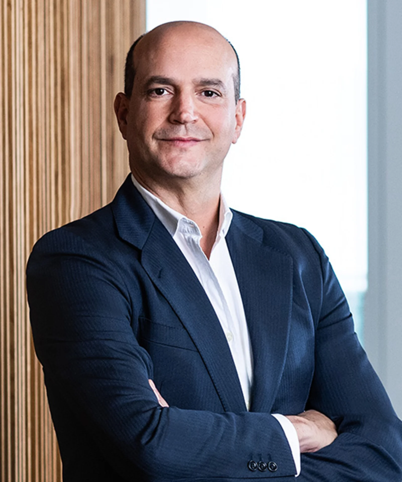 Professional portrait of Manuel Lavin, wearing a dark suit with arms crossed and a confident smile.