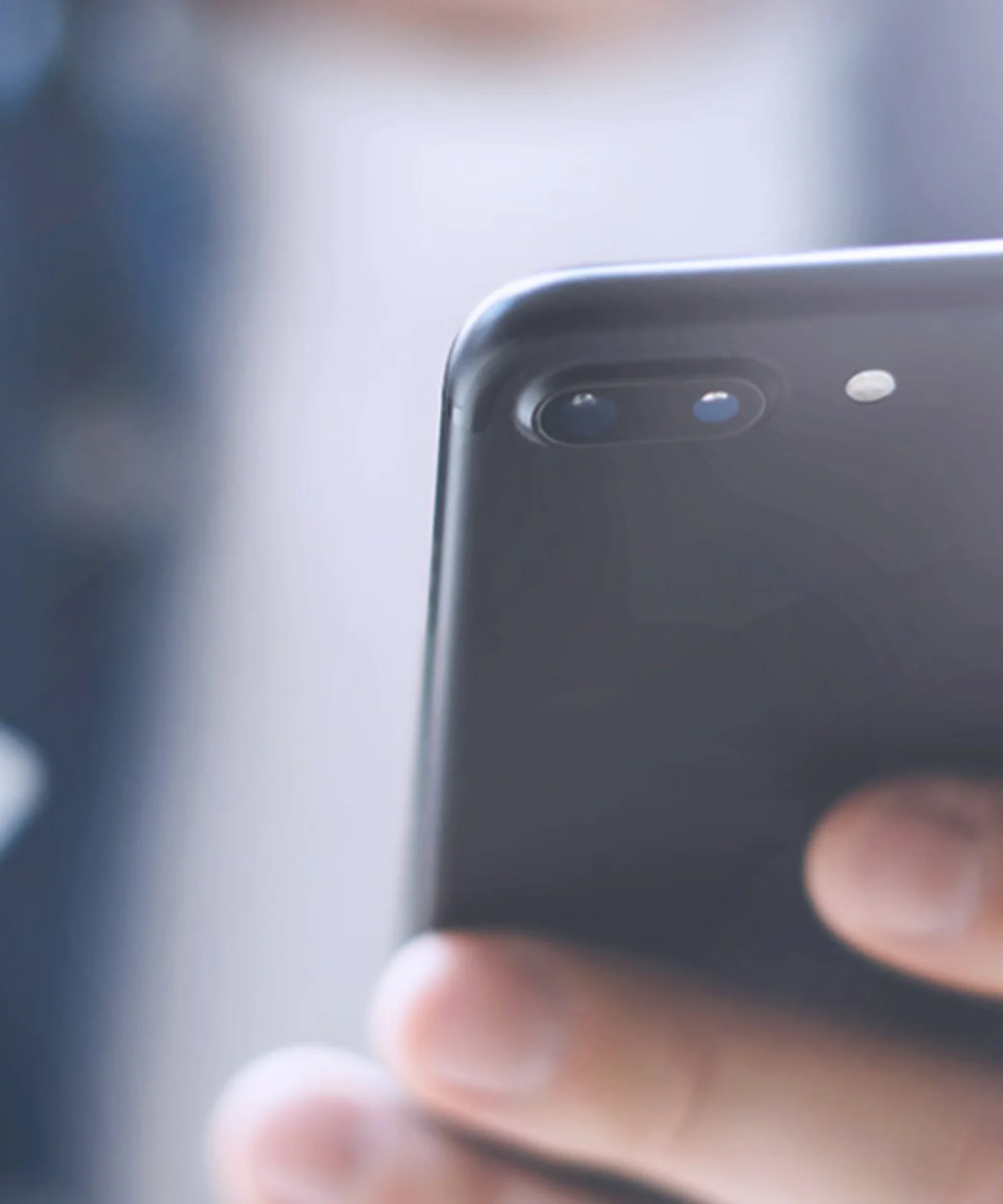 Close-up of a man holding a smartphone in one hand and a credit card in the other, representing mobile payment and online shopping.