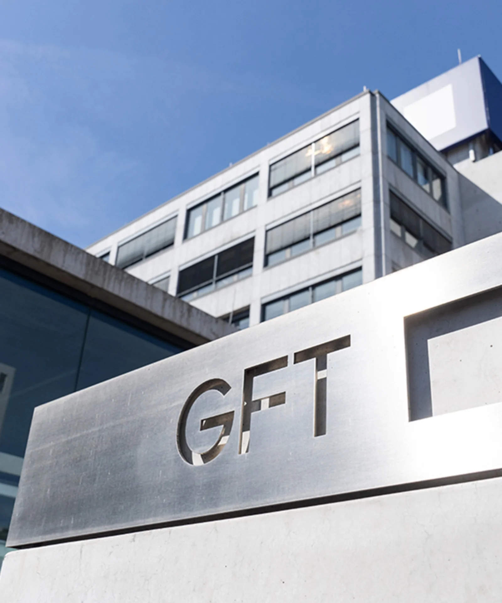 Une vue de l&#039;extérieur du bâtiment du siège social de GFT, présentant le logo de l&#039;entreprise et son design architectural moderne.