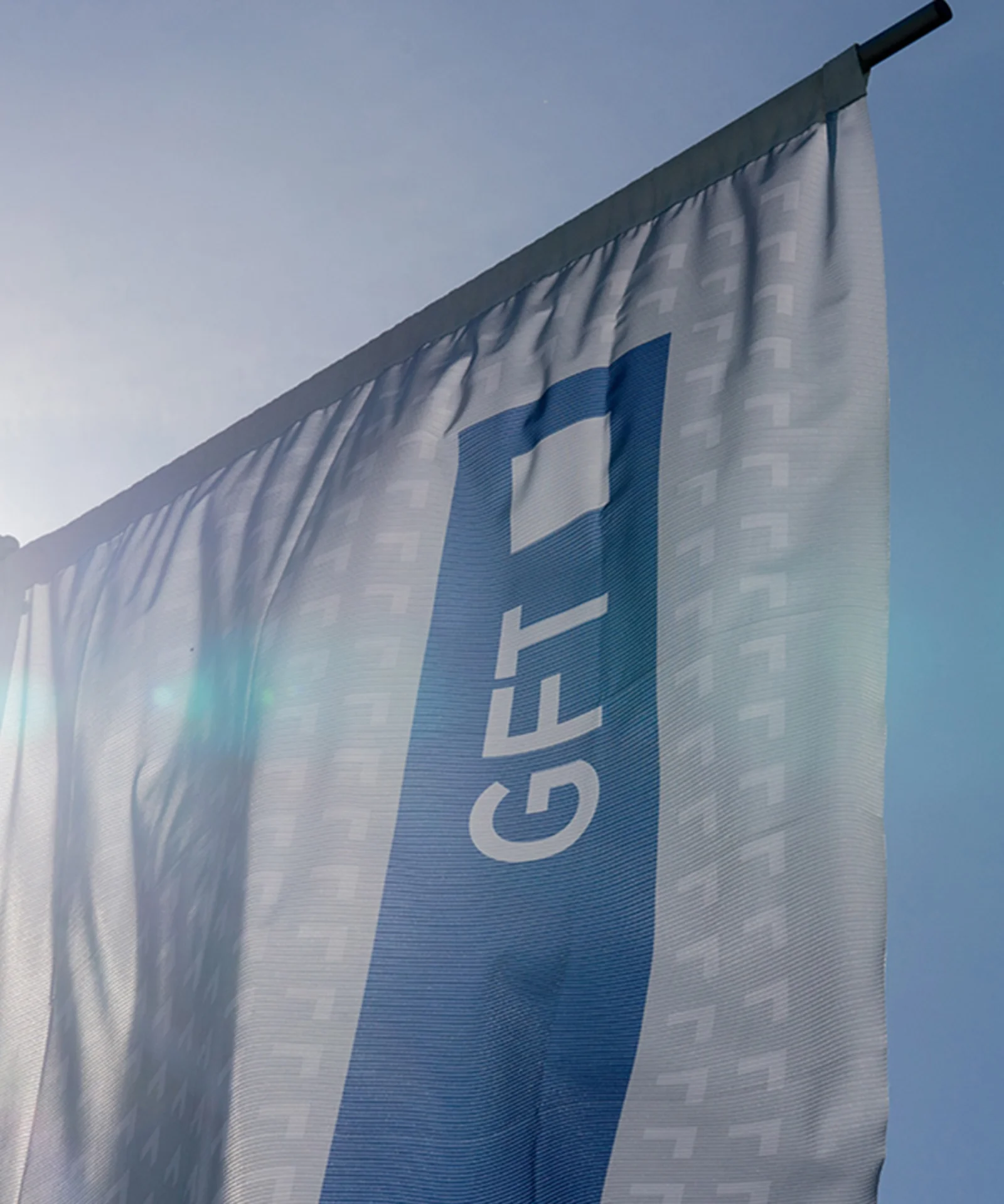 La bandera de GFT ondea orgullosamente a la luz del sol, lo que representa la fuerte presencia de la empresa y su dedicación a la innovación y la excelencia en el sector tecnológico. Esta imagen captura la esencia de la identidad corporativa de GFT y su compromiso de liderar la industria con soluciones de vanguardia y un enfoque vanguardista.