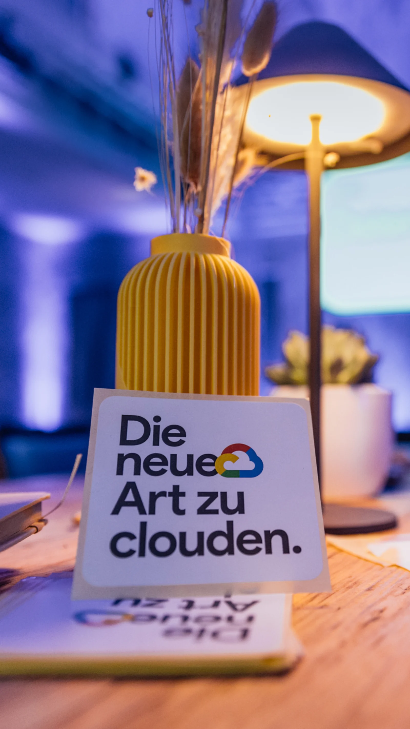 Nahaufnahme eines Tisches mit dem Schriftzug „Die neue Art zu clouden“ in einem atmosphärisch beleuchteten Raum auf dem Google Cloud Summit.