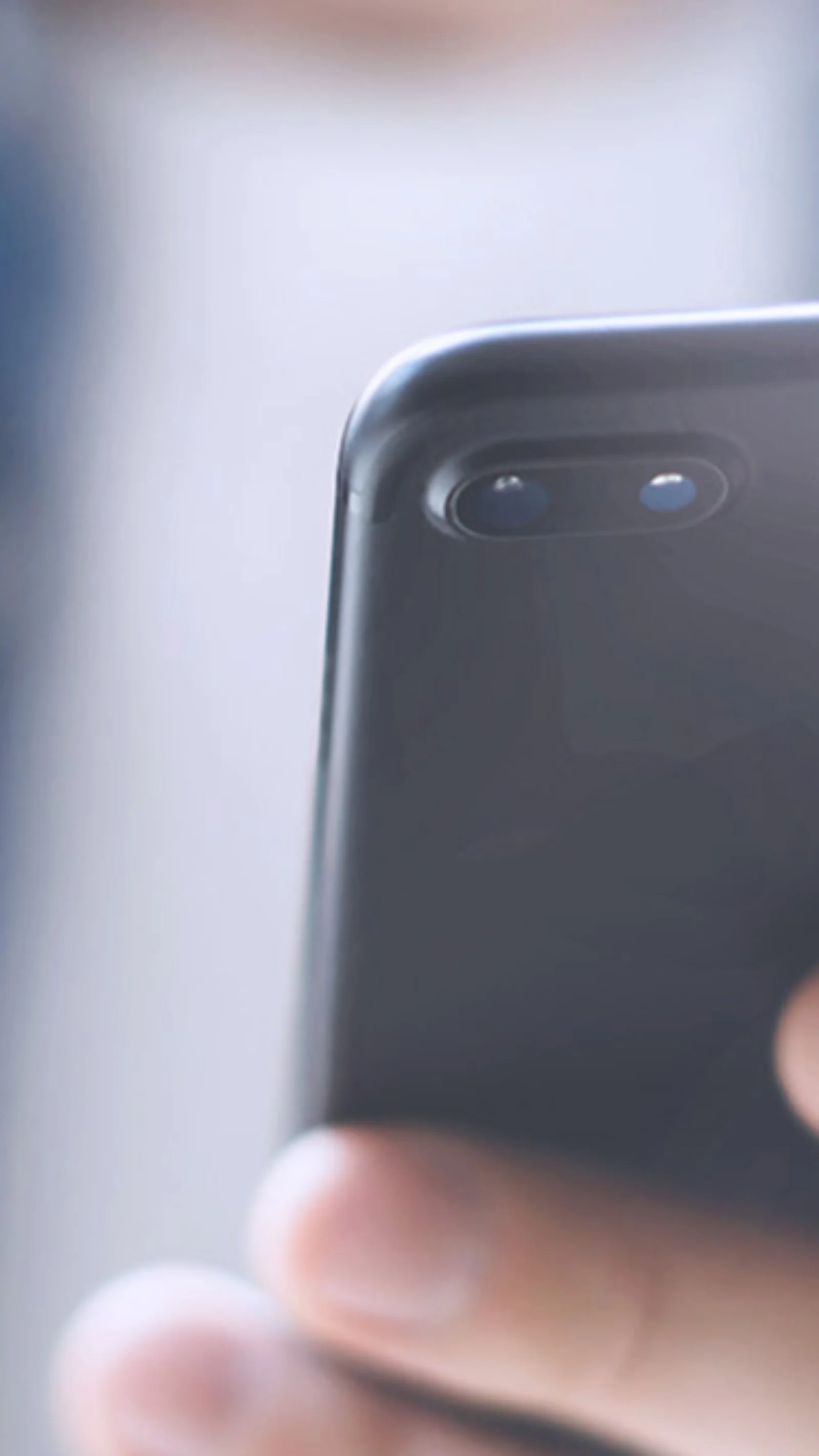 Close-up of a man holding a smartphone in one hand and a credit card in the other, representing mobile payment and online shopping.