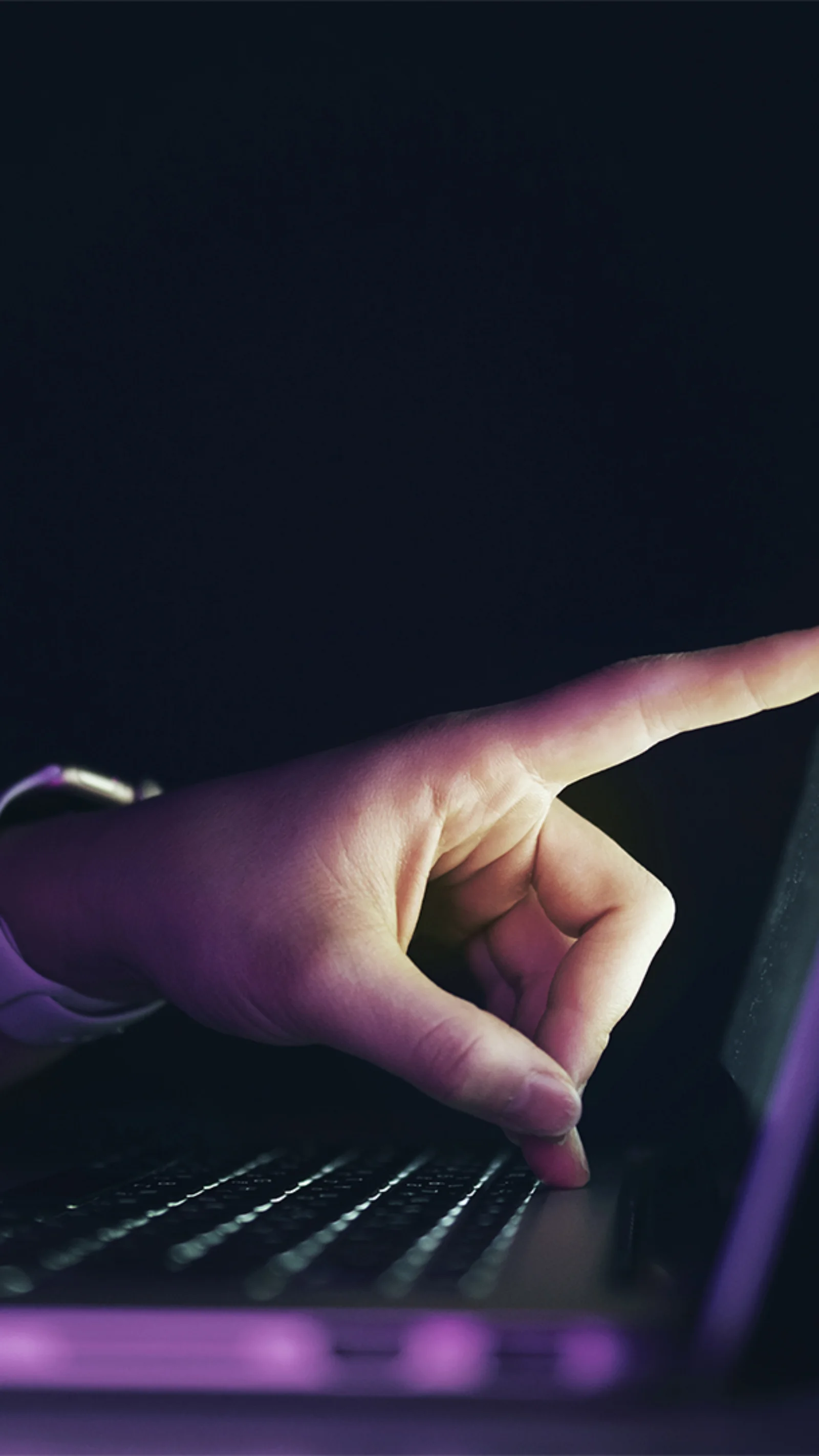 A close-up of a hand interacting with a laptop touchscreen in a dimly lit environment, representing seamless user experience and digital responsiveness.