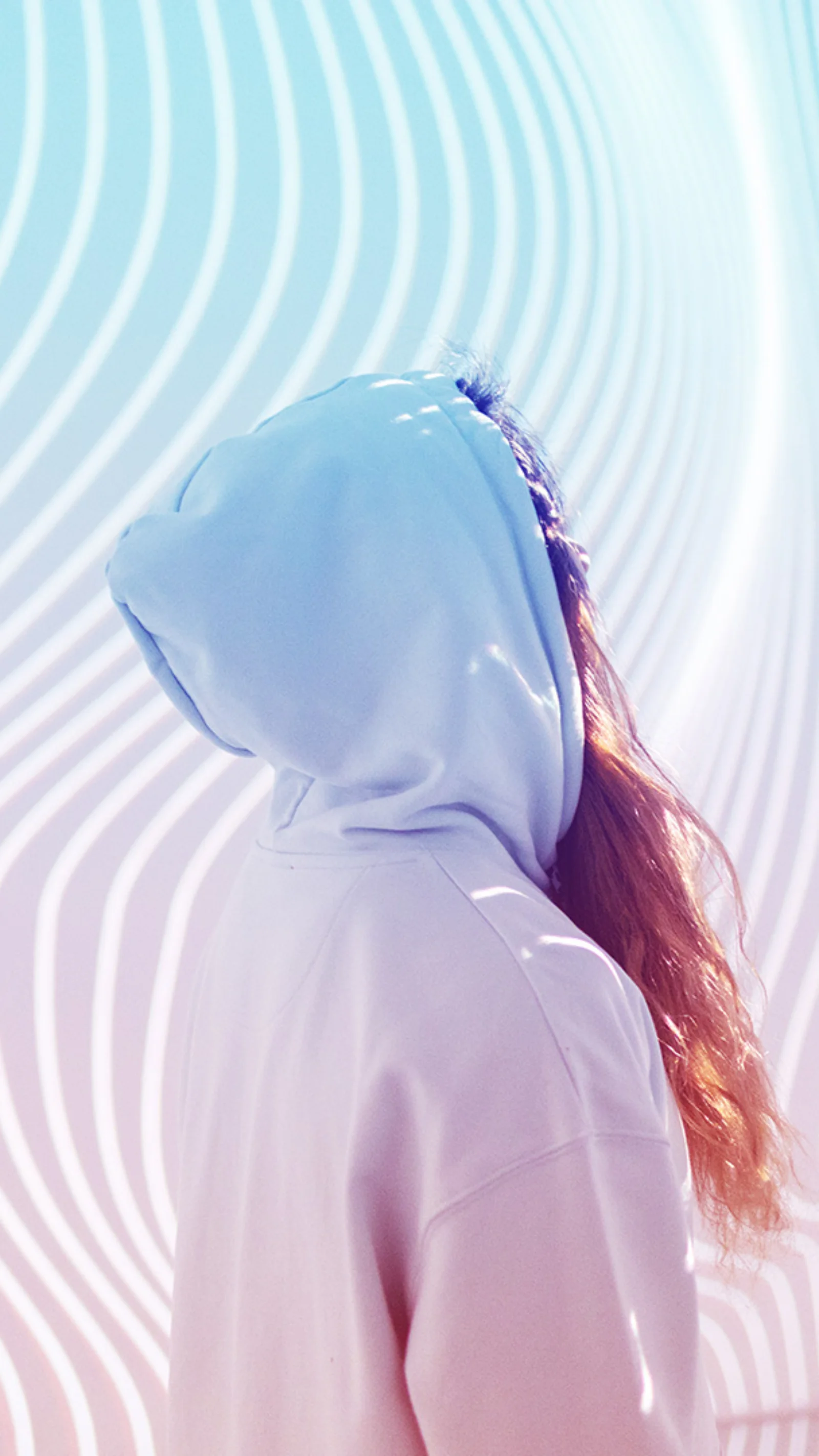 A person in a hooded sweatshirt standing in front of a modern, abstract background with flowing lines and vibrant colours, symbolising the innovative transformation in the insurance industry through mainframe modernisation.