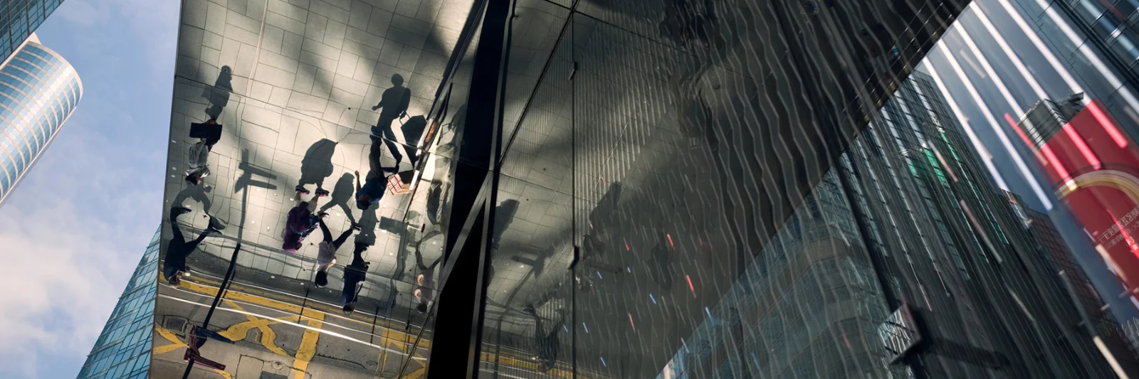 Reflection of cityscape and pedestrians in a glass building facade, symbolising modern financial interconnectedness.