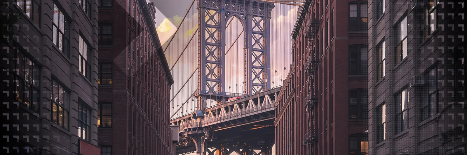 Scenic view of the Manhattan Bridge between high-rise buildings at sunset, highlighting New York City&#039;s iconic architecture and urban charm. Perfect representation of urban innovation and infrastructure on the GFT website.