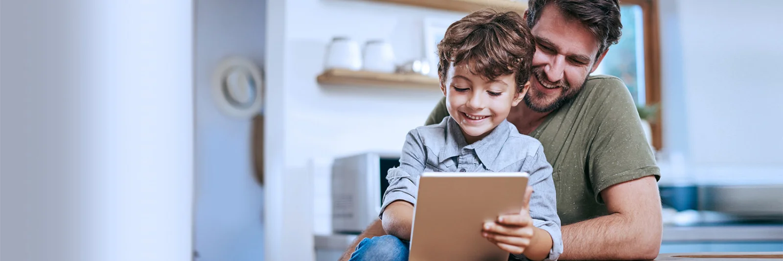 A smiling father and his young son enjoying time together using a tablet, illustrating a digital platform designed for children.