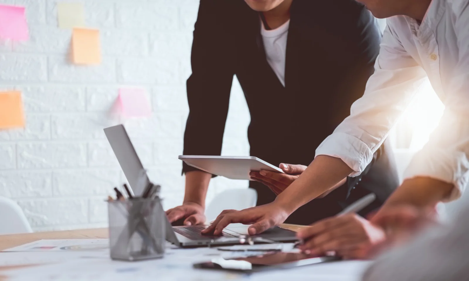 Ein Team von Fachleuten bespricht Strategien zur Cloud-Kostenkontrolle. Mehrere Personen arbeiten zusammen an Laptops und Tablets.