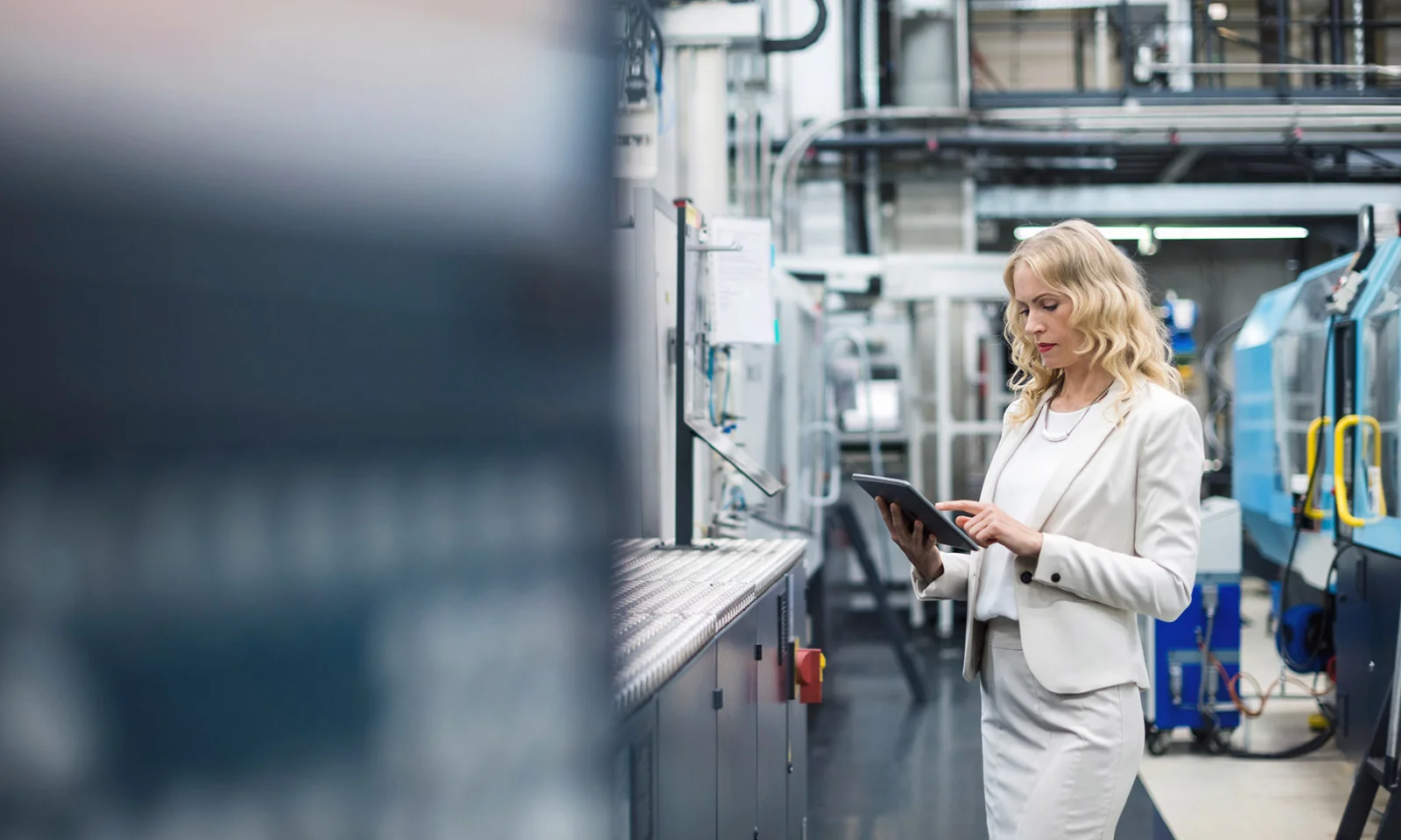 Businesswoman leveraging technology in a manufacturing facility, highlighting the integration of digital tools in industrial management and operations.