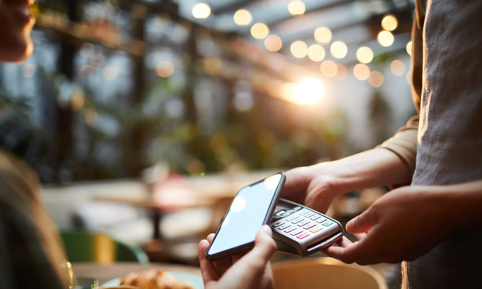  A close-up shot of a mobile payment transaction in a modern cafe, illustrating GFT&#039;s innovative digital payment solutions. This image represents GFT&#039;s commitment to advancing fintech and seamless customer experiences through cutting-edge technology.