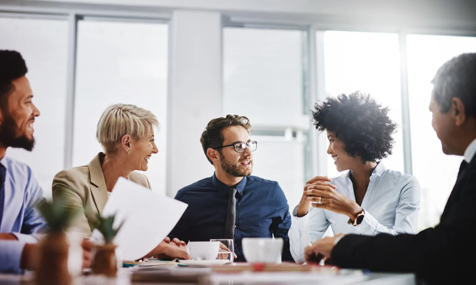 Na GFT, o trabalho em equipe impulsiona a inovação. Esta imagem mostra um grupo diverso de profissionais colaborando em uma reunião, destacando a cultura inclusiva, criativa e inovadora que alimenta o sucesso da GFT em fornecer soluções digitais de ponta.