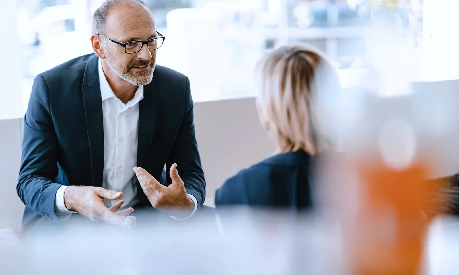 Teaser image for analyst reports showing a business discussion between two professionals, with a focus on a man explaining his point.