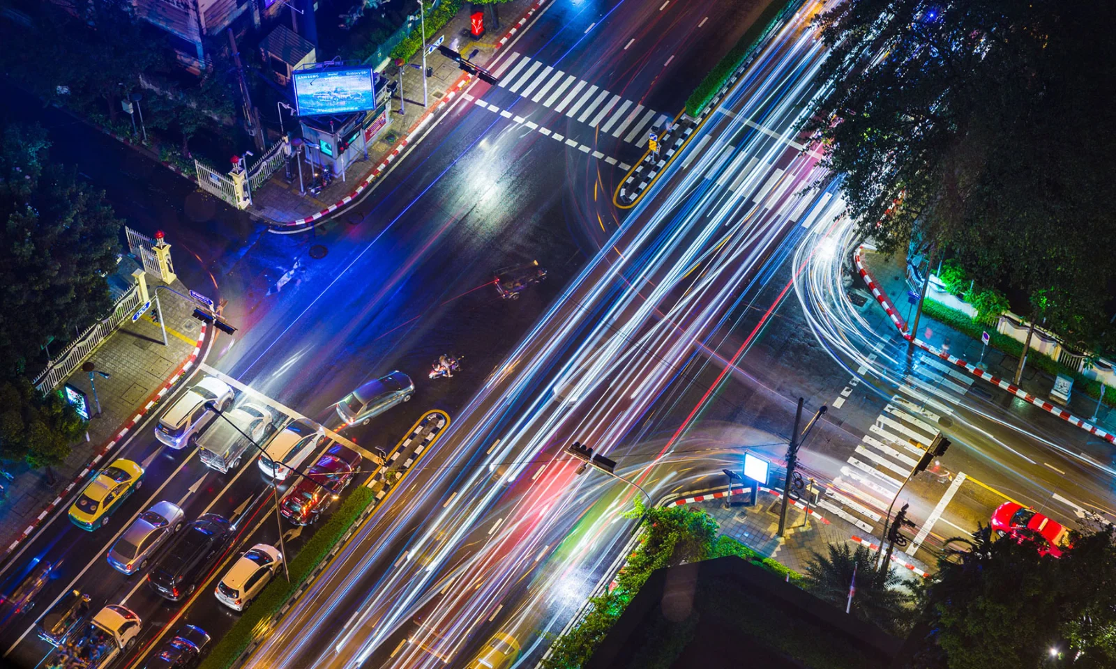 Una vista aérea de una intersección concurrida de la ciudad por la noche, con rayos de luz que representan el tráfico en rápido movimiento y simbolizan la naturaleza dinámica de las soluciones de seguros personalizadas.