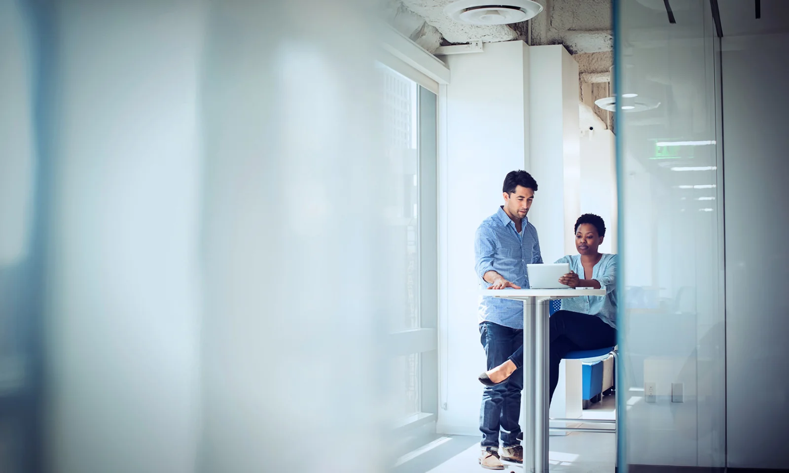 Two professionals collaborating on a laptop in a modern office setting