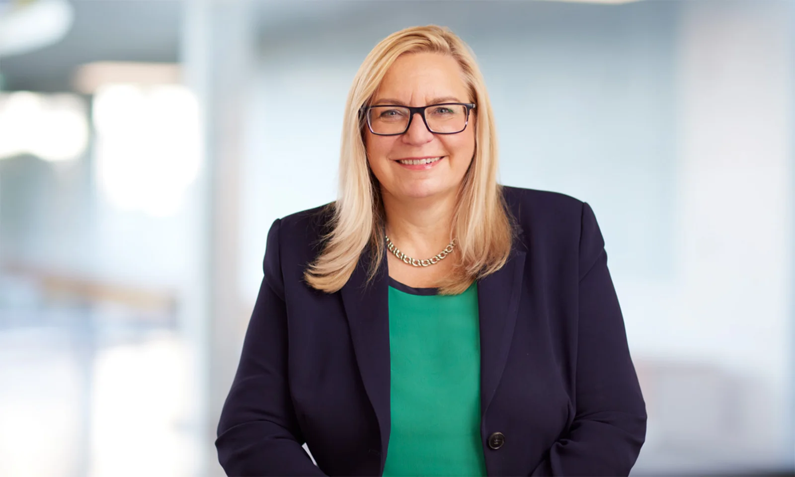 Marika Lulay, a member of the GFT Administrative Board, smiling confidently while wearing a navy blazer and green top, symbolising leadership and expertise in the technology industry.