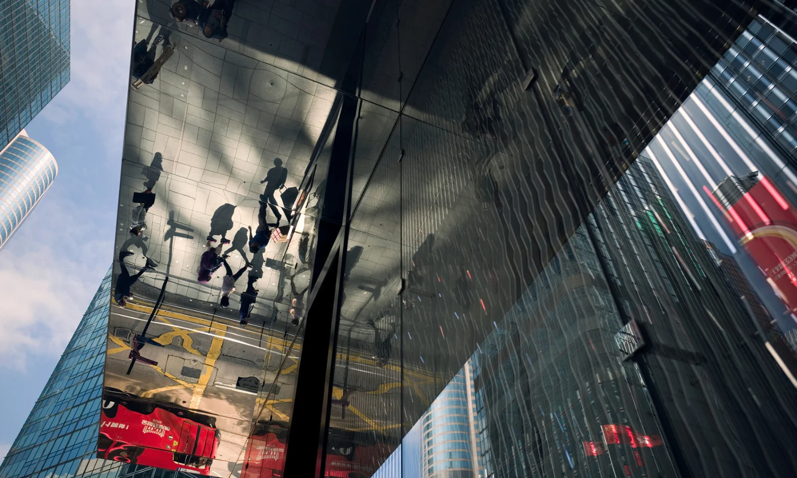 Reflection of cityscape and pedestrians in a glass building facade, symbolising modern financial interconnectedness.