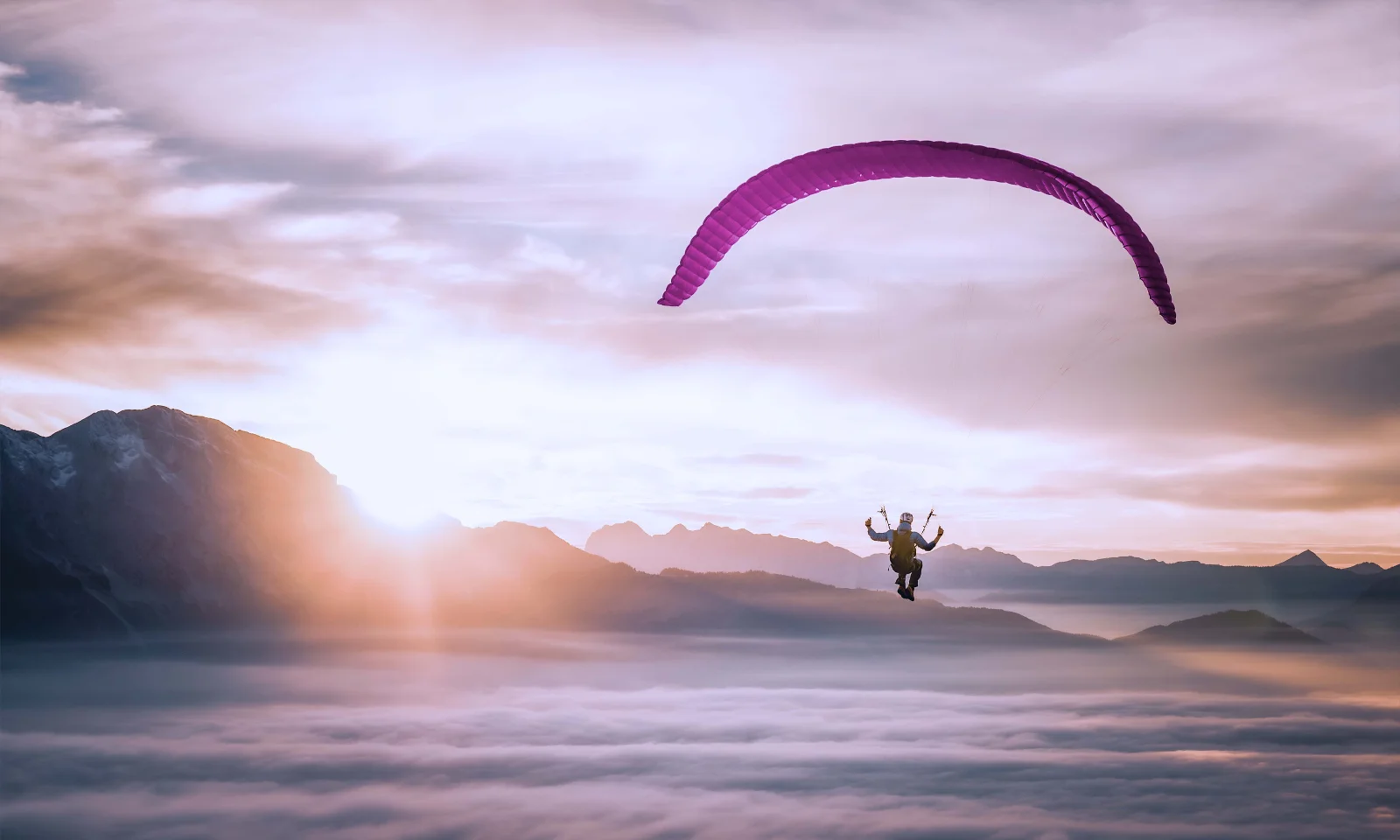 Ein Paraglider schwebt über den Wolken bei Sonnenaufgang, symbolisiert die Flexibilität und Freiheit in der Cloud-Nutzung, während gleichzeitig die Kontrolle über Kosten erhalten bleibt.