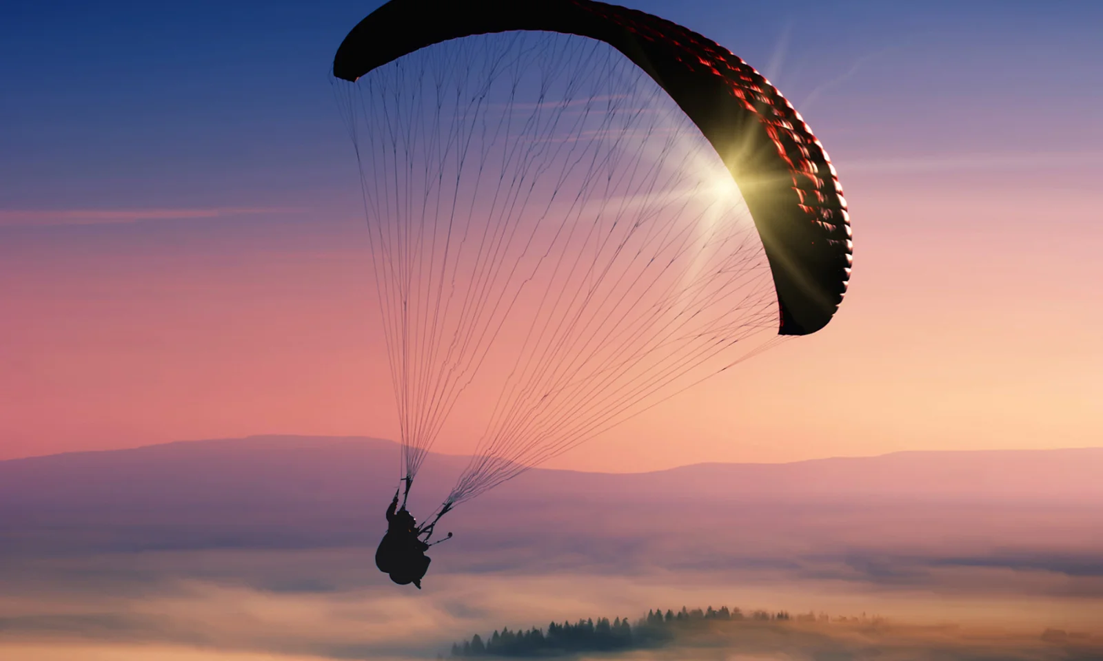 Una silueta impresionante de un parapente volando en un cielo de atardecer vibrante, que simboliza la libertad, la agilidad y las amplias posibilidades que ofrecen las soluciones híbridas y multicloud.