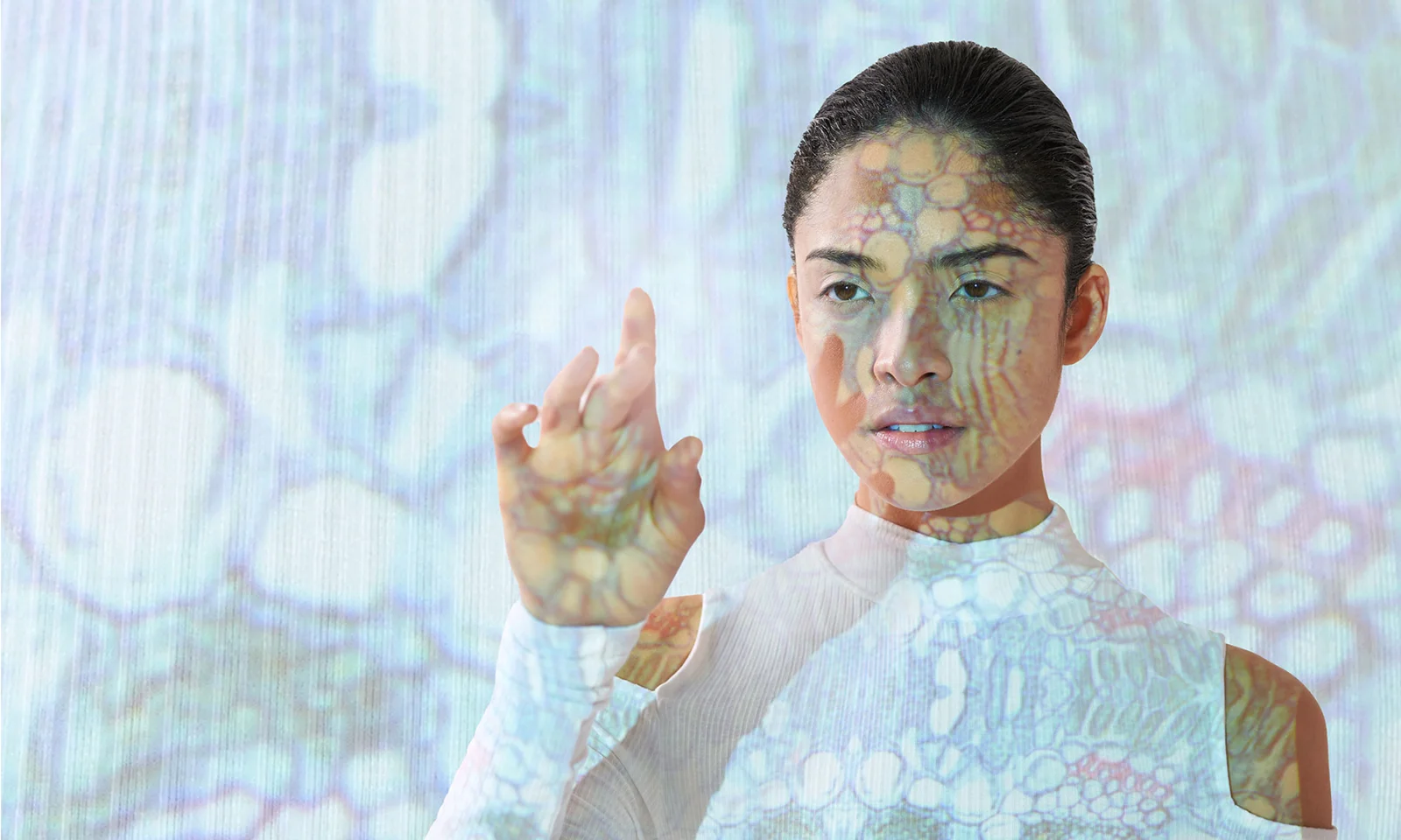 This key visual showcases a woman with digital patterns projected onto her face and body, symbolizing the integration of artificial intelligence and human interaction. The image represents the cutting-edge advancements in AI technology and its seamless blending with human capabilities.