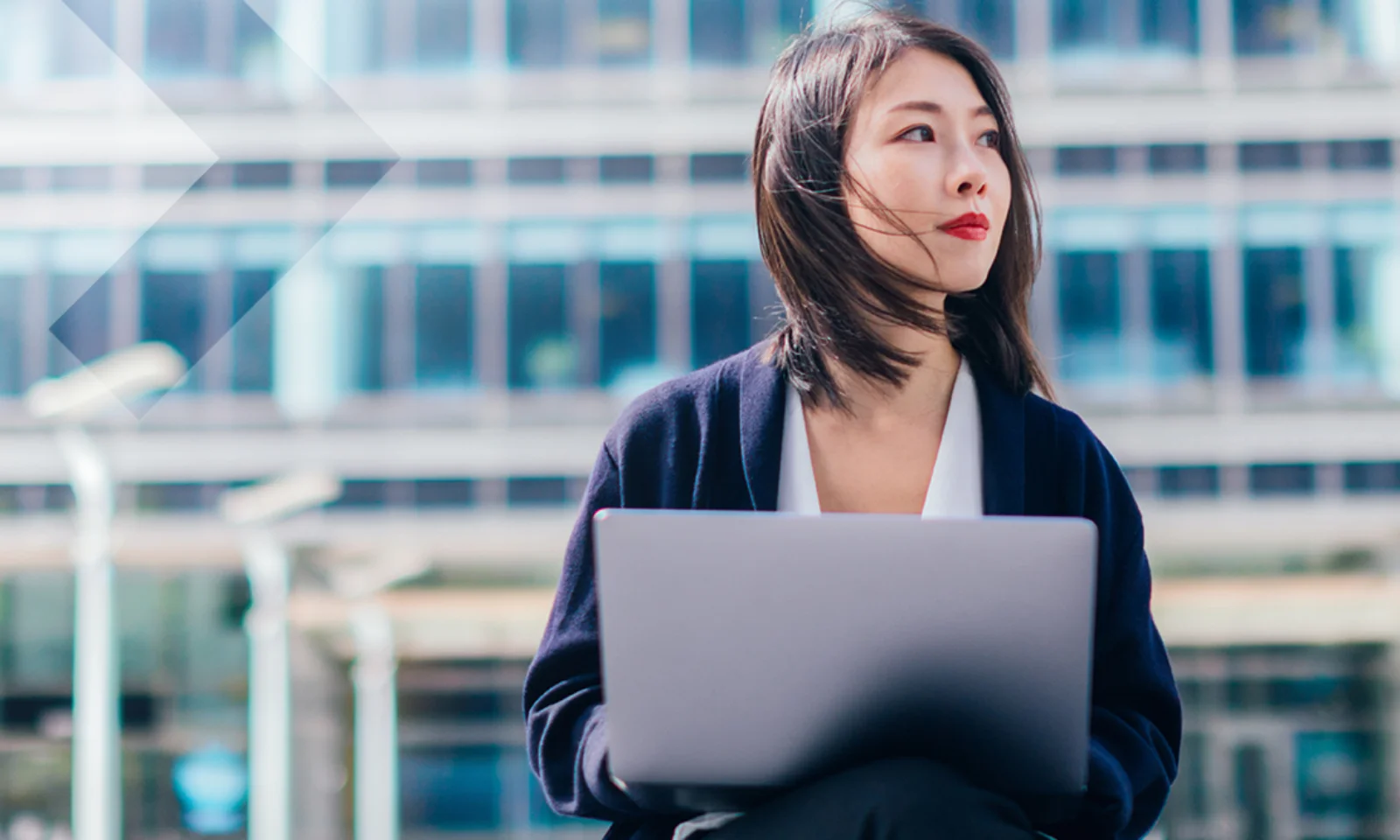 Headerbild einer Geschäftsfrau mit Laptop vor einem modernen Bürogebäude. Symbolisiert die T+1-Roadmap und die digitale Transformation der Finanzmärkte in Europa.