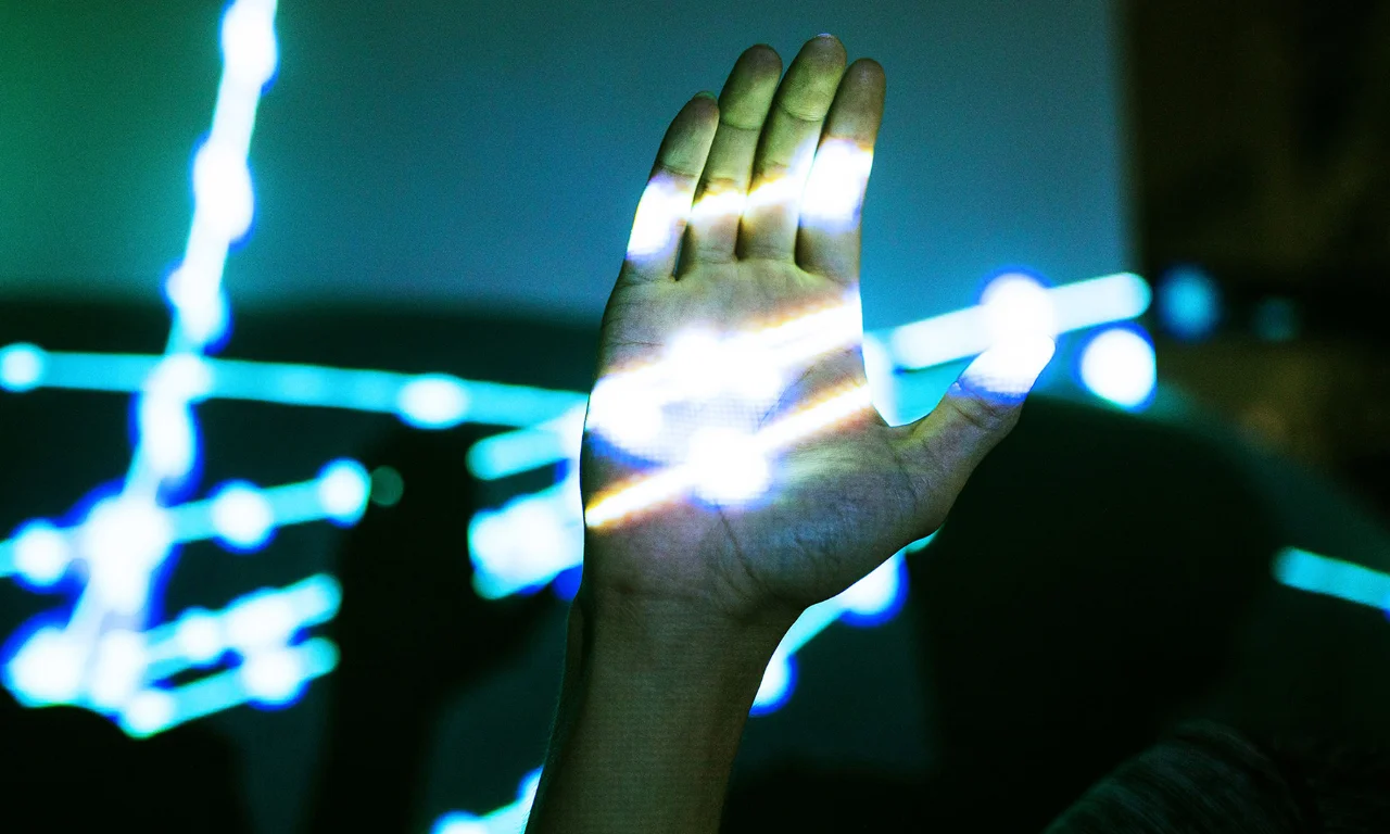 The image showcases a hand illuminated with intricate digital light patterns, symbolizing the innovative and interconnected nature of the Sphinx Open project. The patterns of light streaming across the hand evoke a sense of digital transformation and connectivity. This visual representation emphasizes the project&#039;s focus on open-source development, technology integration, and the human touch in technological advancements. The vibrant colors and dynamic light effects create a futuristic and engaging atmosphere, aligning with the cutting-edge ethos of Sphinx Open.