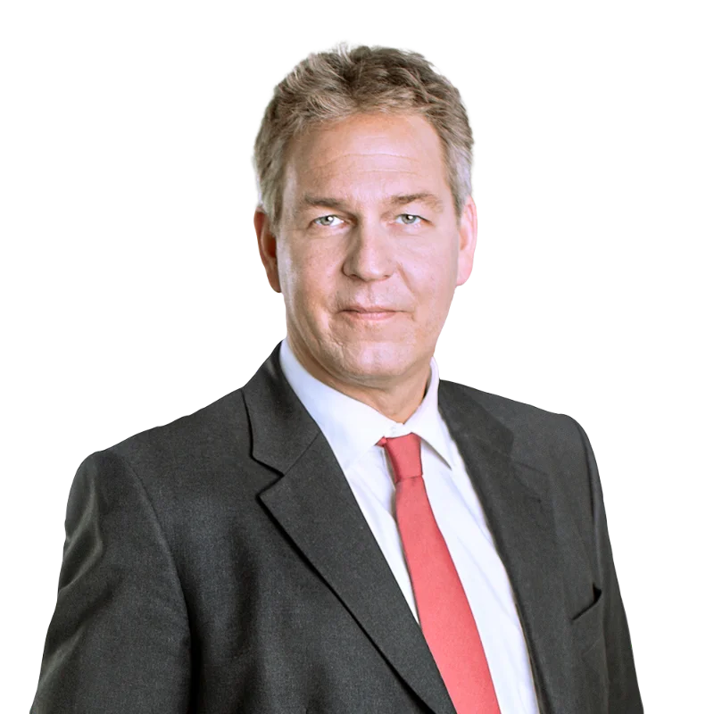 Portrait of Jens-Thorsten Rauer in a dark suit and red tie.